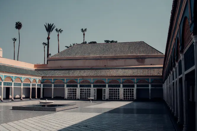The grand tiled courtyard of Bahia Palace under a clear blue sky in Marrakech.