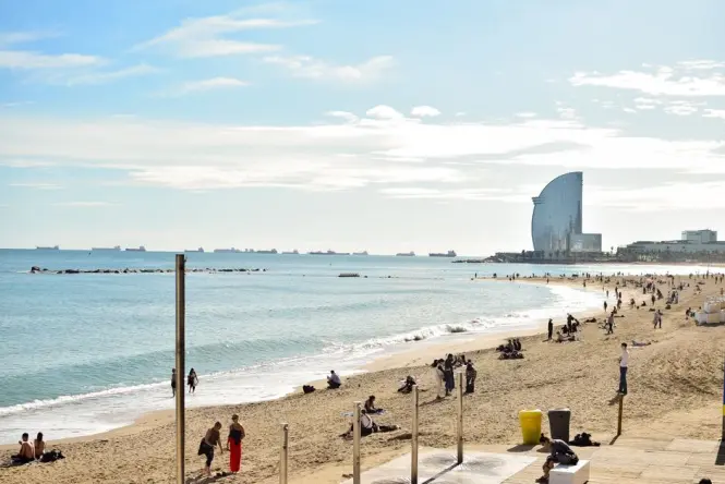 People walking along the sunny beach boardwalk in Barceloneta