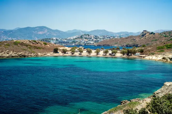 A sunny beach resort scene in Bodrum with clear turquoise waters and lounge chairs.