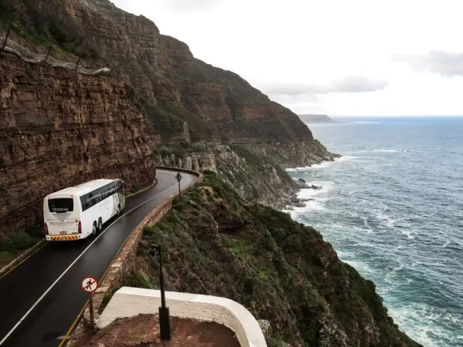 A car driving along the dramatic coastal cliffs of Chapman's Peak in Cape Town