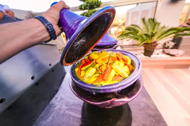 A steaming traditional clay pot tagine served with fresh bread.