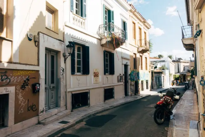 A narrow, picturesque street in the historic Plaka neighbourhood with flowers and outdoor dining tables