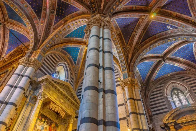 Detailed medieval frescoes on a brick archway in an Italian basilica