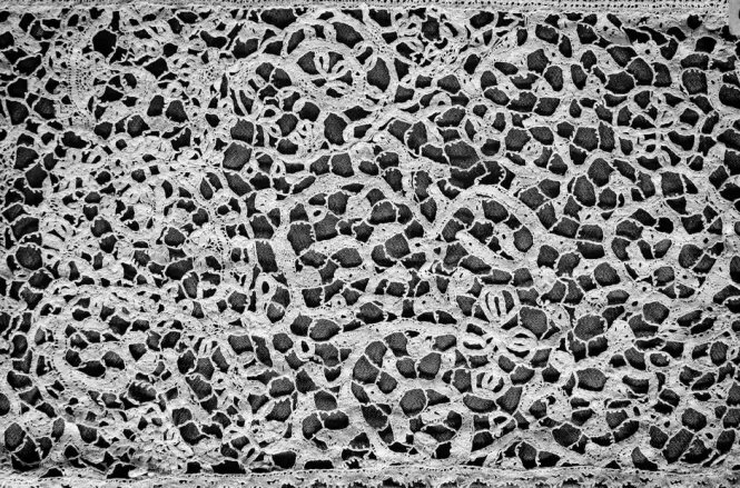 Intricate, authentic handmade Burano needle lace displayed on a dark background