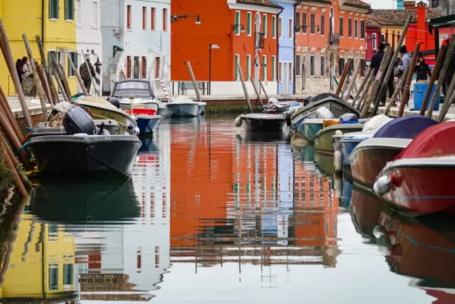An outdoor dining table next to a canal on the island of Burano