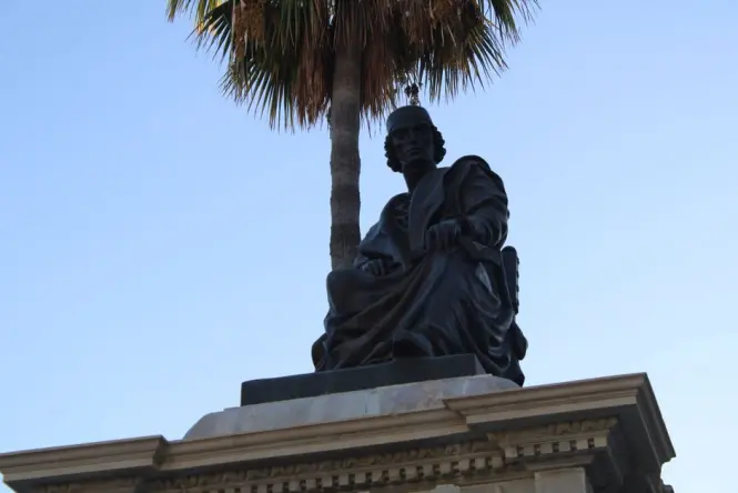 Bronze statue of a literary figure seated at a café table