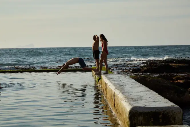 Families swimming in the tidal pool at the southern end of Camps Bay Beach