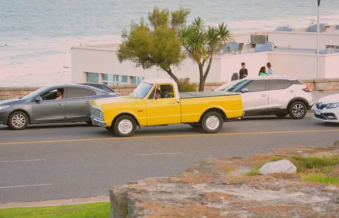 Cars parked along Victoria Road facing Camps Bay Beach
