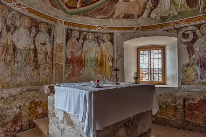 A quiet, solemn chapel interior with candles and historical religious icons in Sicily