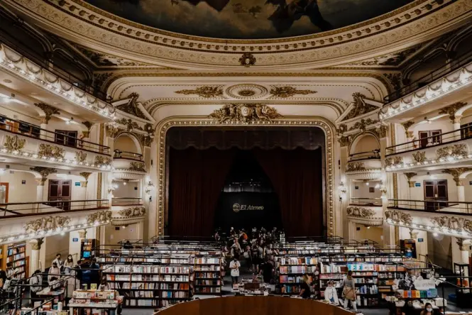 Cafe tables set on the former stage of El Ateneo Grand Splendid with the original curtain behind