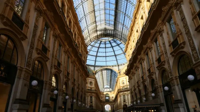 A quiet early morning view inside Galleria Vittorio Emanuele II with soft sunlight streaming through the roof