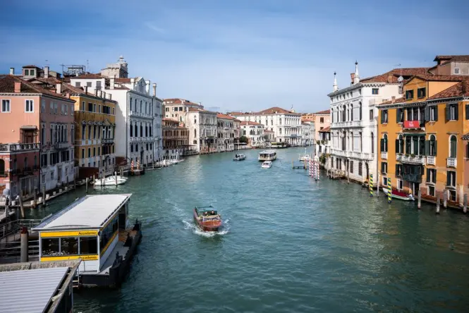 A Venice vaporetto water bus passing under the historic wooden Accademia Bridge