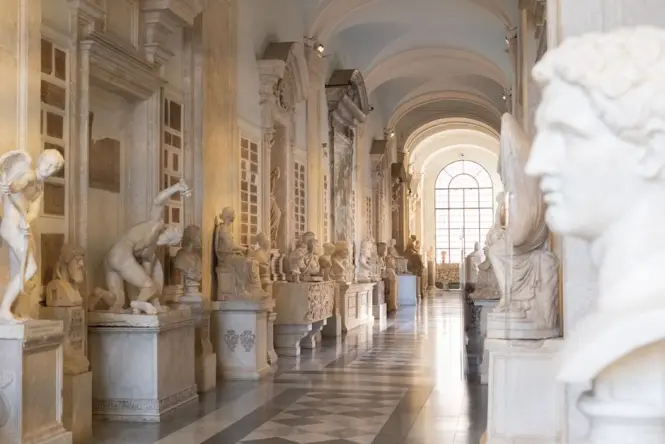 Exhibition room inside a classic Italian museum showing grand paintings mounted on high walls