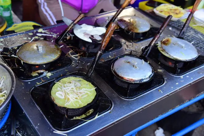 Bindaetteok mung bean pancakes frying on a griddle at Gwangjang Market