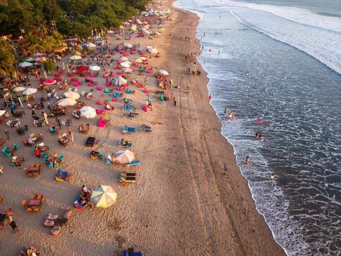 Tourists enjoying sunset sitting on plastic chairs at Kuta Beach