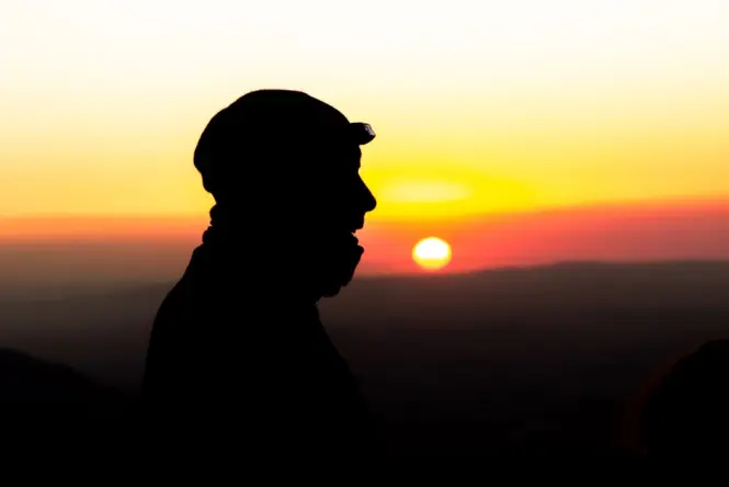 Hikers ascending Lion's Head before sunrise with headlamps lit