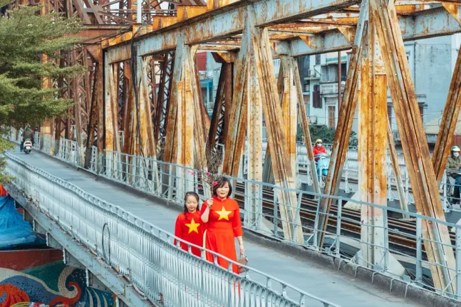 Pedestrians walking along the narrow footpath of Long Bien Bridge