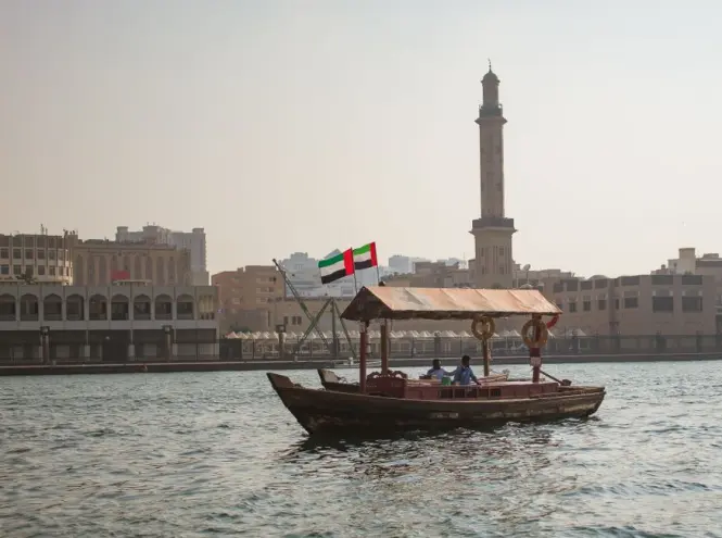 Traditional wooden abra boat crossing a waterway between hotel wings at Madinat Jumeirah