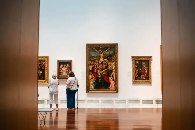 Visitors looking at large paintings in a museum
