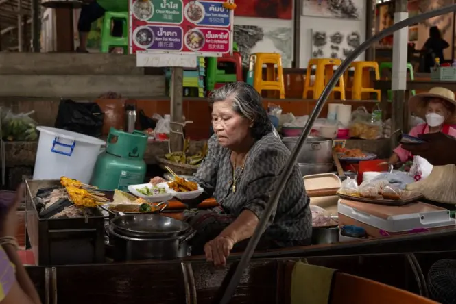 A cook preparing fresh Pad Thai in a busy food court