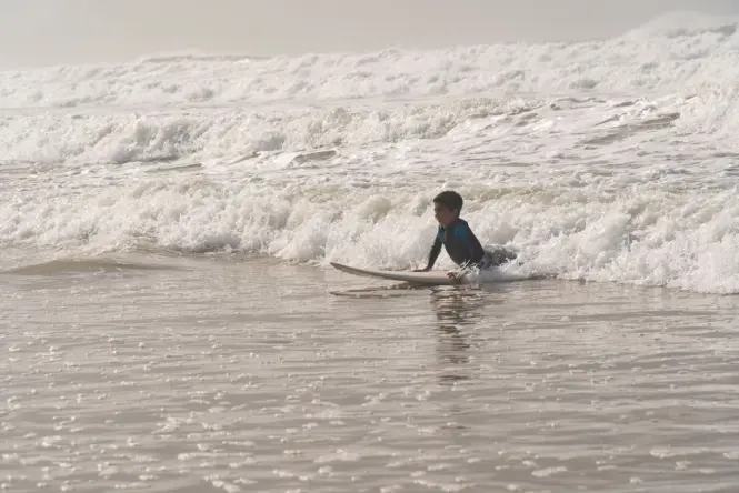 Beginner surfer catching a small wave at Surfers Corner in Muizenberg