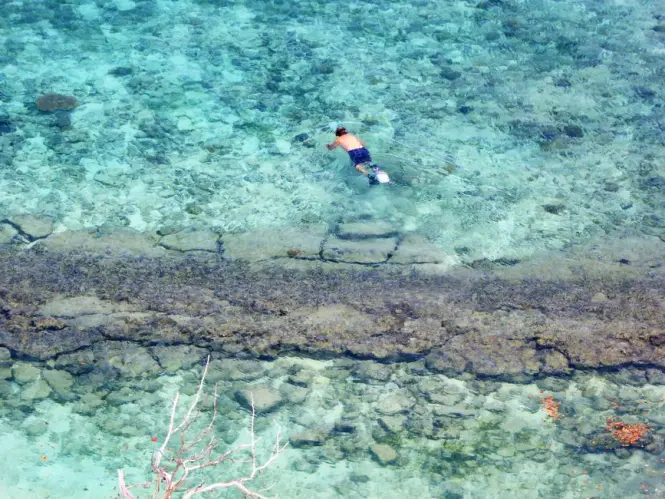 Snorkeling gear on rocks beside clear cove water