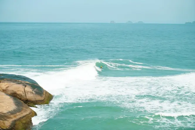 Surfer paddling out at the Arpoador point break in Rio de Janeiro