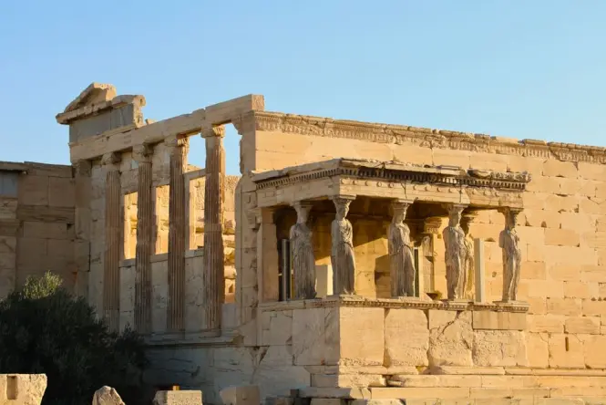 Photographer capturing the Parthenon from a rocky viewpoint at golden hour