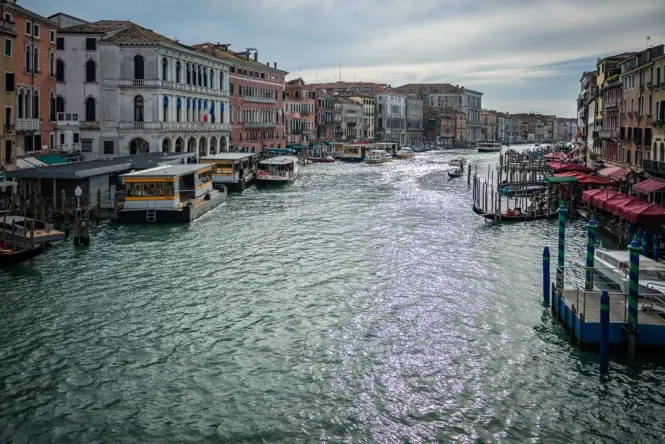 tourists walking on elevated wooden walkways in flooded Venice