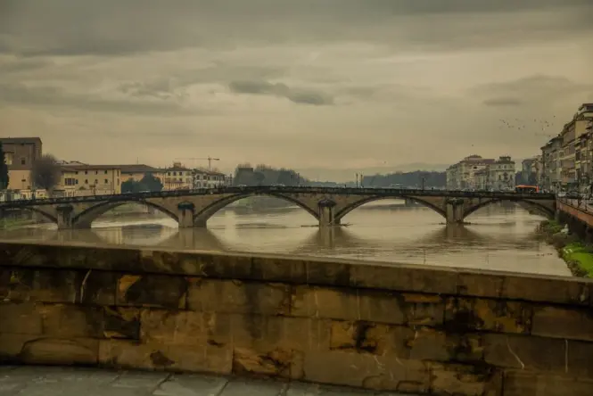 The classic side view of Ponte Vecchio with its colorful houses reflecting in the river, taken from Ponte Santa Trinita