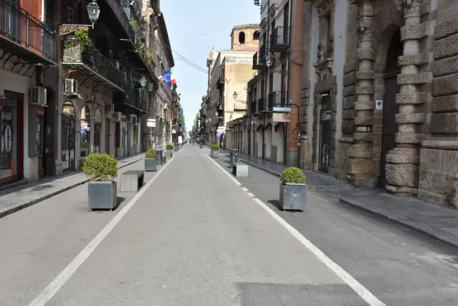 People walking through the pedestrianized stone intersection of Quattro Canti