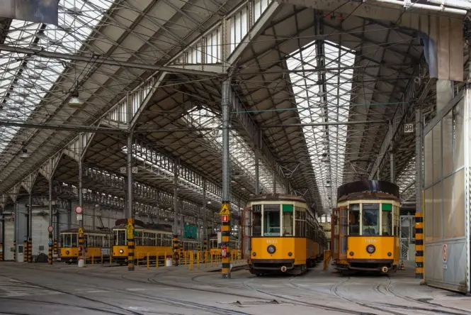 An old-fashioned orange tram driving past historic buildings on Corso Magenta in Milan