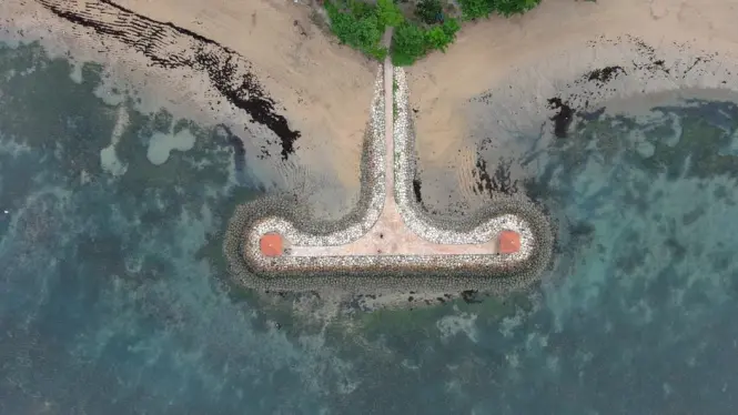 Paved promenade along Sanur Beach lined with shade trees