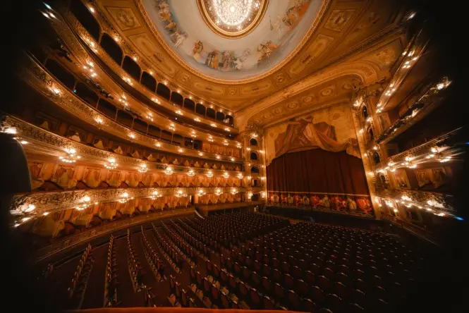 The gold and red velvet tiers of boxes inside the Great Hall of Teatro Massimo