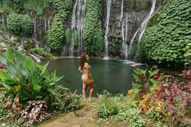 Visitors swimming in the natural pool at a Bali waterfall
