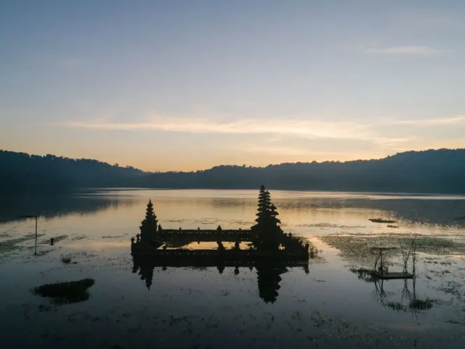 Mist rolling over Lake Bratan in front of the main meru tower at Ulun Danu Beratan Temple in early morning light