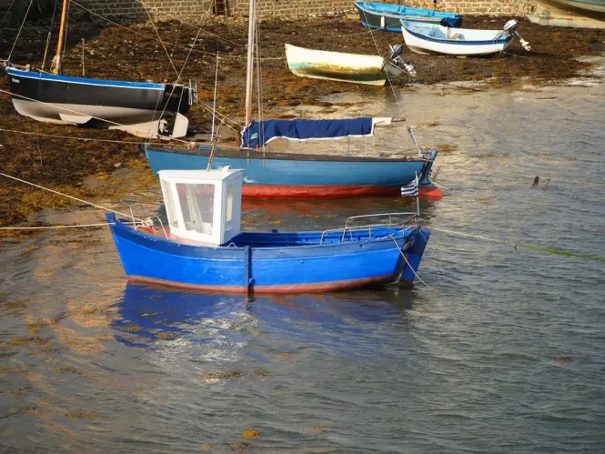 Pastel-colored wooden fishing boats moored in a narrow rocky cove