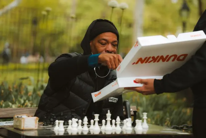 Chess players at outdoor stone tables in a park